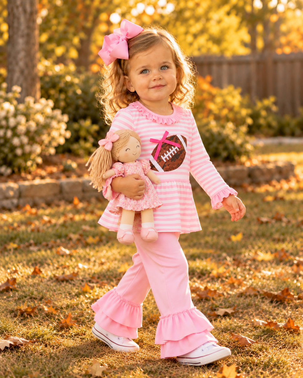 Girl wearing pink striped ruffle top and pink tiered ruffle pant set with bow