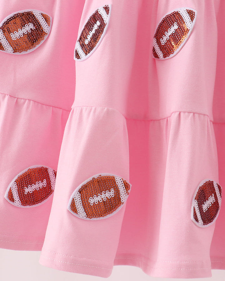 Pink tiered ruffle dress with multiple football sequin patches across the skirt