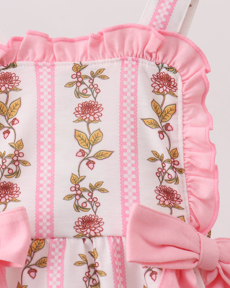 Pink and white baby romper with floral embroidery on a wooden surface