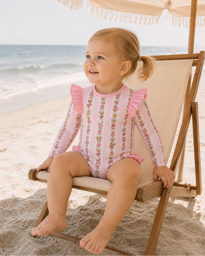 Young girl sitting on a chair under a beach umbrella on the beach