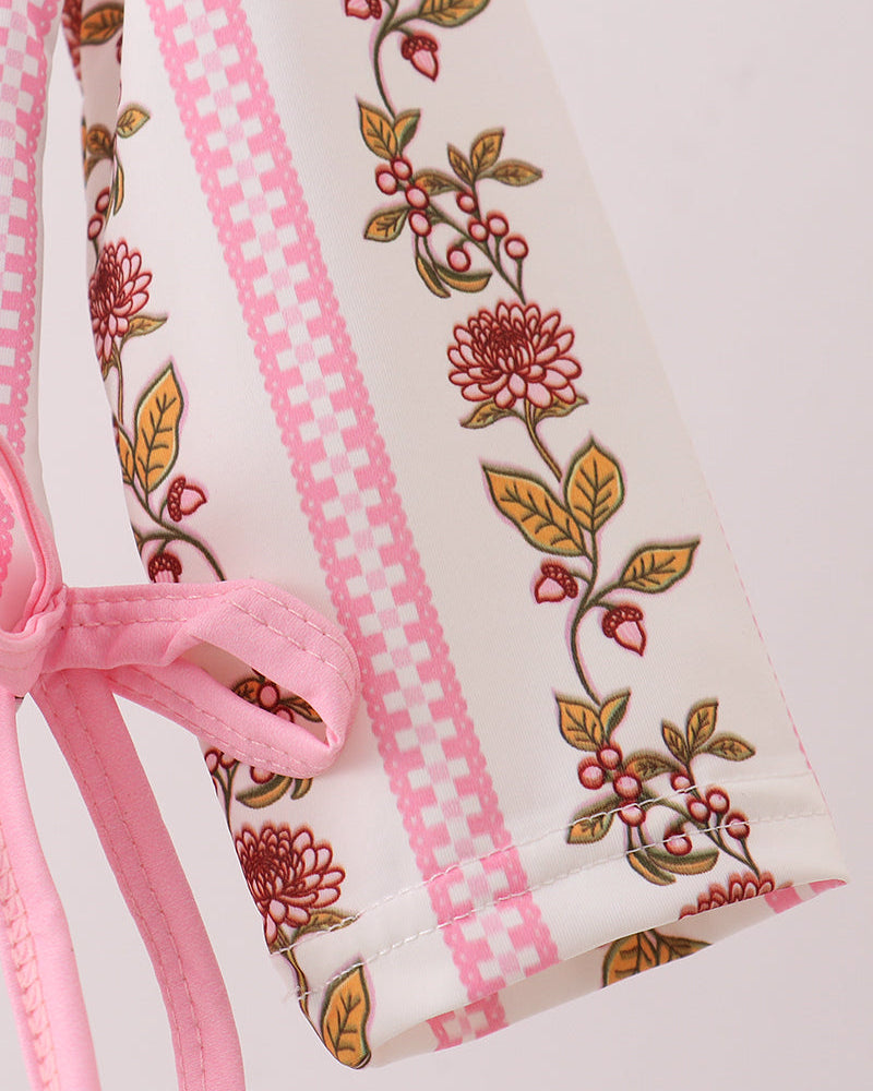 Close-up of a garment with floral embroidery and pink ribbon on a light background