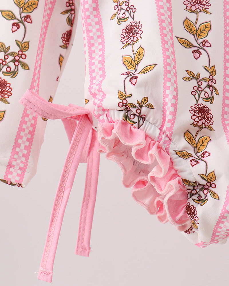 Close-up of a pink and white garment with floral embroidery on a light gray background