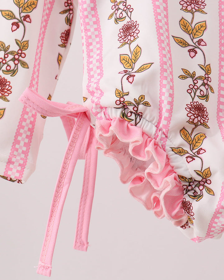 Close-up of a pink and white garment with floral embroidery on a light gray background