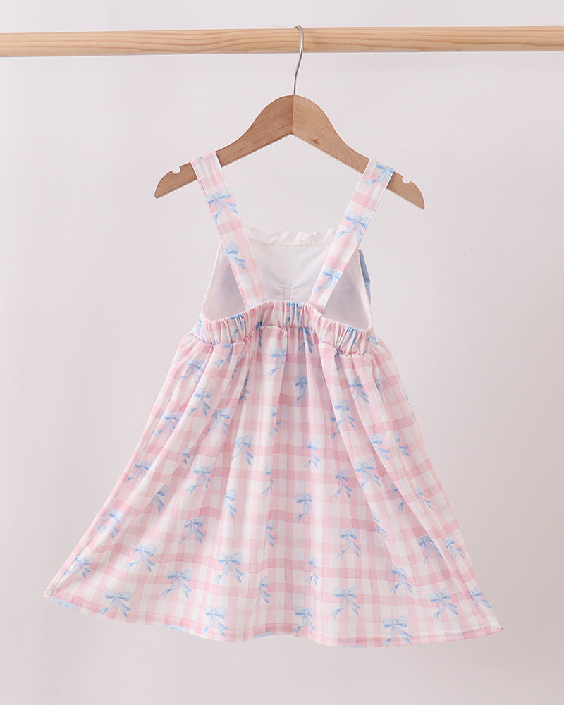 Pink checkered dress with floral pattern on a hanger against a white wall