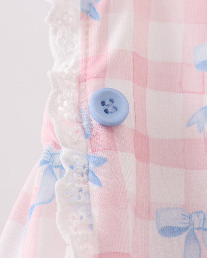 Close-up of a pink checkered fabric with blue floral patterns and a button on a white background