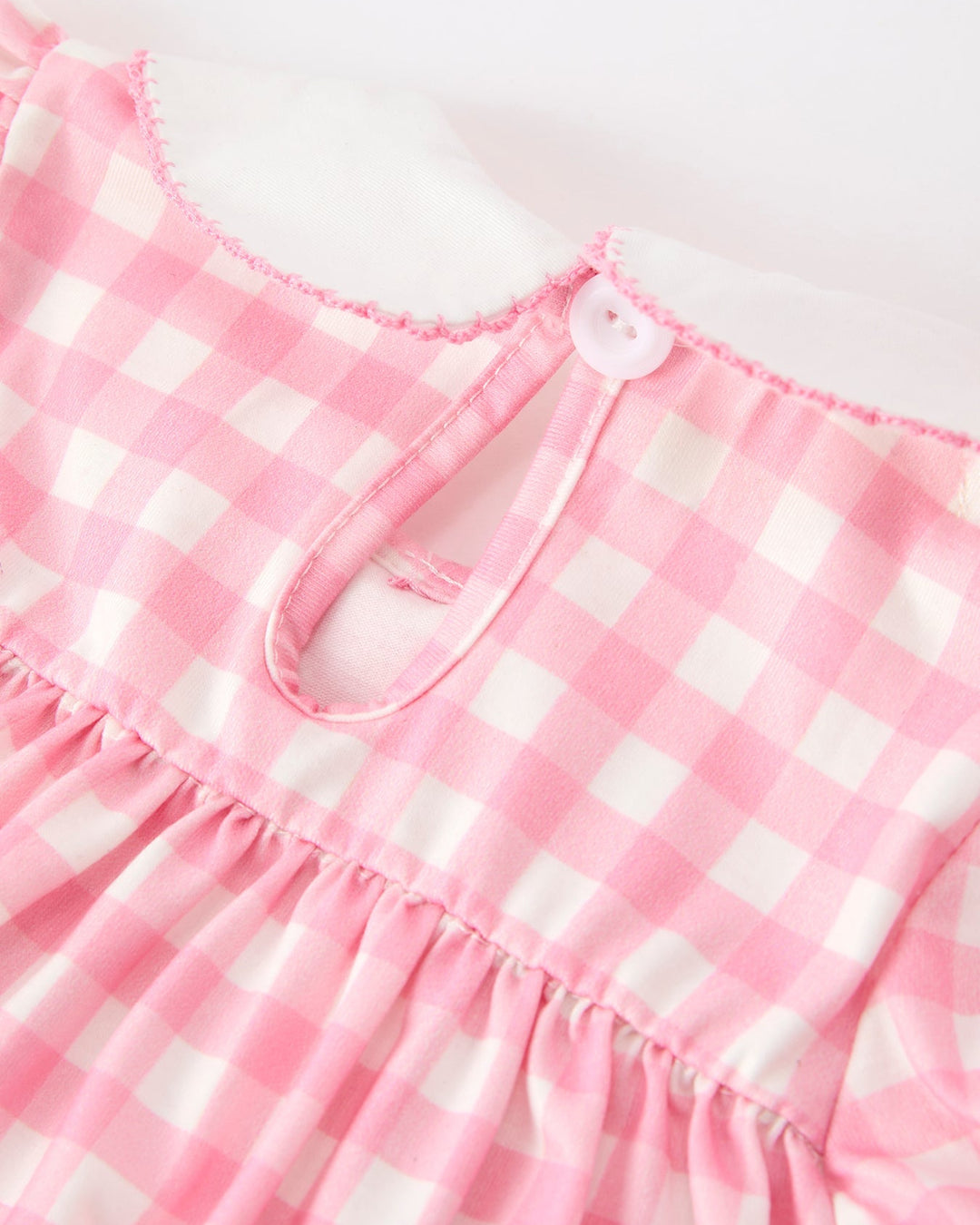 Close-up of girls pink gingham dress neckline with small bow detail