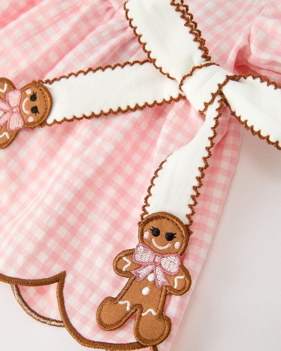 Close-up of pink gingham dress yoke with gingerbread bear applique and scalloped trim