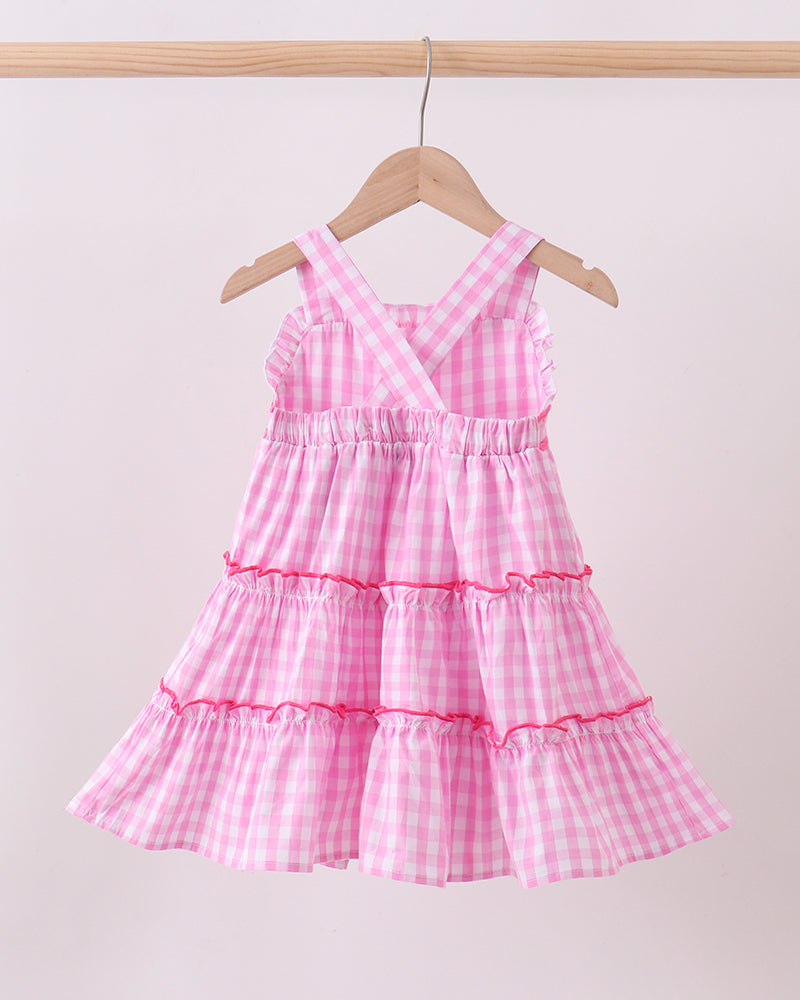 Pink checkered dress on a hanger against a light background