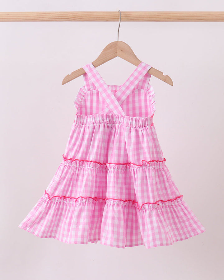Pink checkered dress on a hanger against a light background