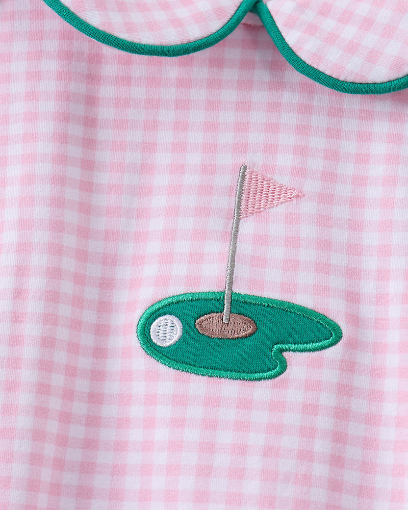 Close-up of a pink and white gingham garment with a green Peter Pan collar and a green embroidered golf green patch on the front.