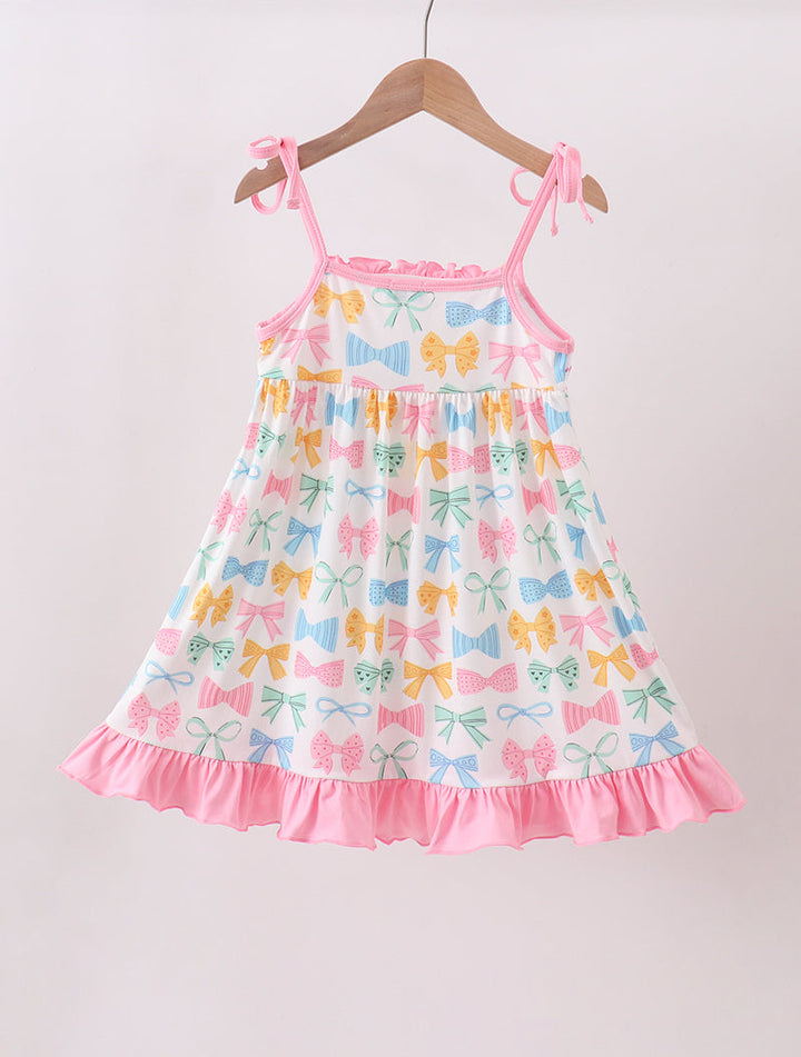 Colorful bow-patterned dress on a hanger against a plain background