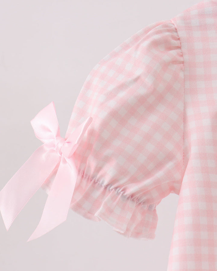 Pink gingham bubble romper sleeve with white bow detail on the shoulder