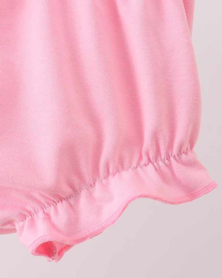 Close-up of a pink garment with a gathered hem on a light gray background