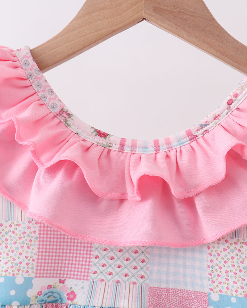 Pink ruffled fabric on a hanger against a patchwork background