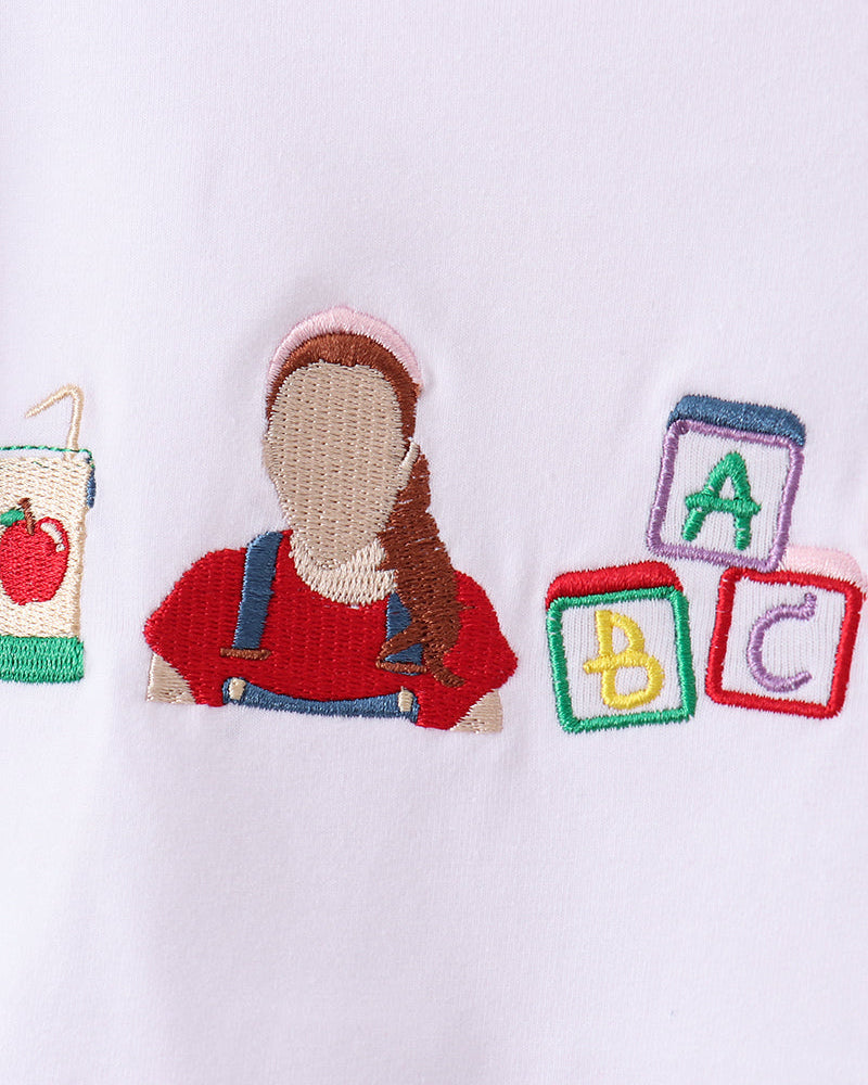 Embroidered ABC and child motif on white fabric