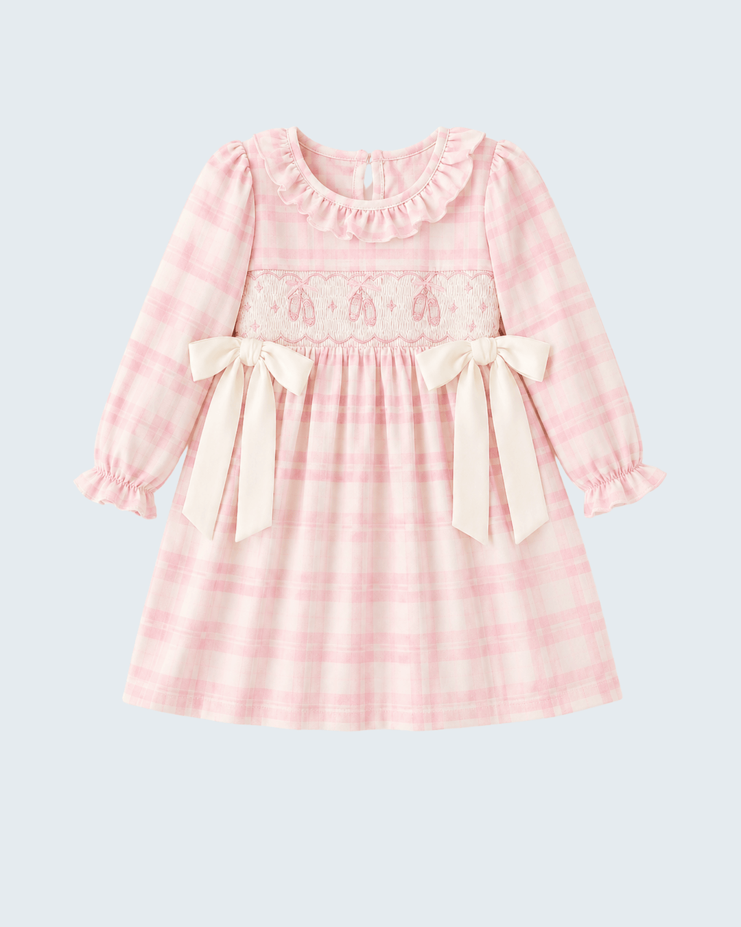 A pink and white plaid long-sleeve baby dress with a ruffled collar, lace smocked chest panel with ribbon motifs, and two cream satin bows at the waist, shown on a light gray background.