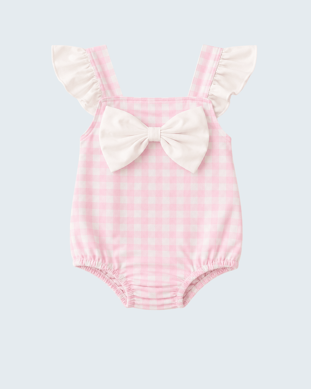 Pink checkered baby romper with ruffled straps and a bow on a light gray background