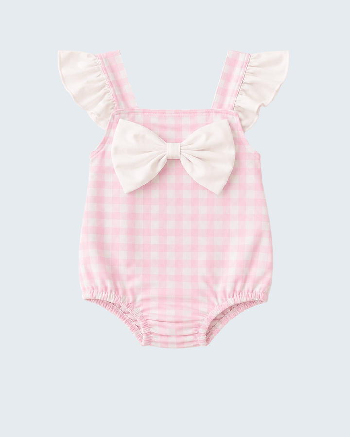 Pink checkered baby romper with ruffled straps and a bow on a light gray background