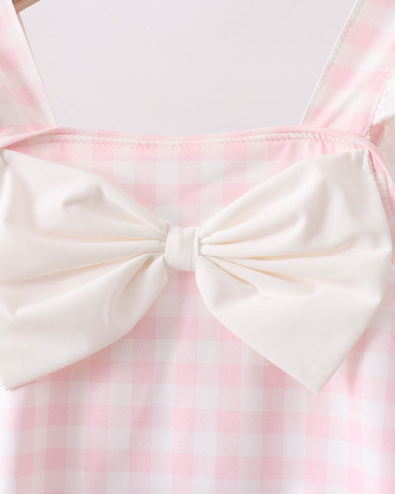 Pink and white checkered dress with a large bow on a hanger