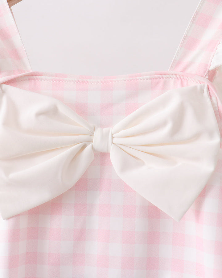 Pink and white checkered dress with a large bow on a hanger