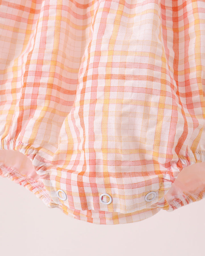 Plaid bubble romper close-up with snap button closure and gathered leg openings