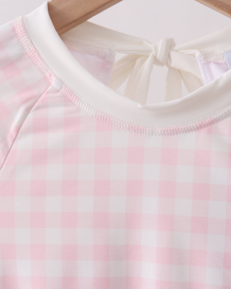 Close-up of a pink and white checkered garment on a wooden hanger.