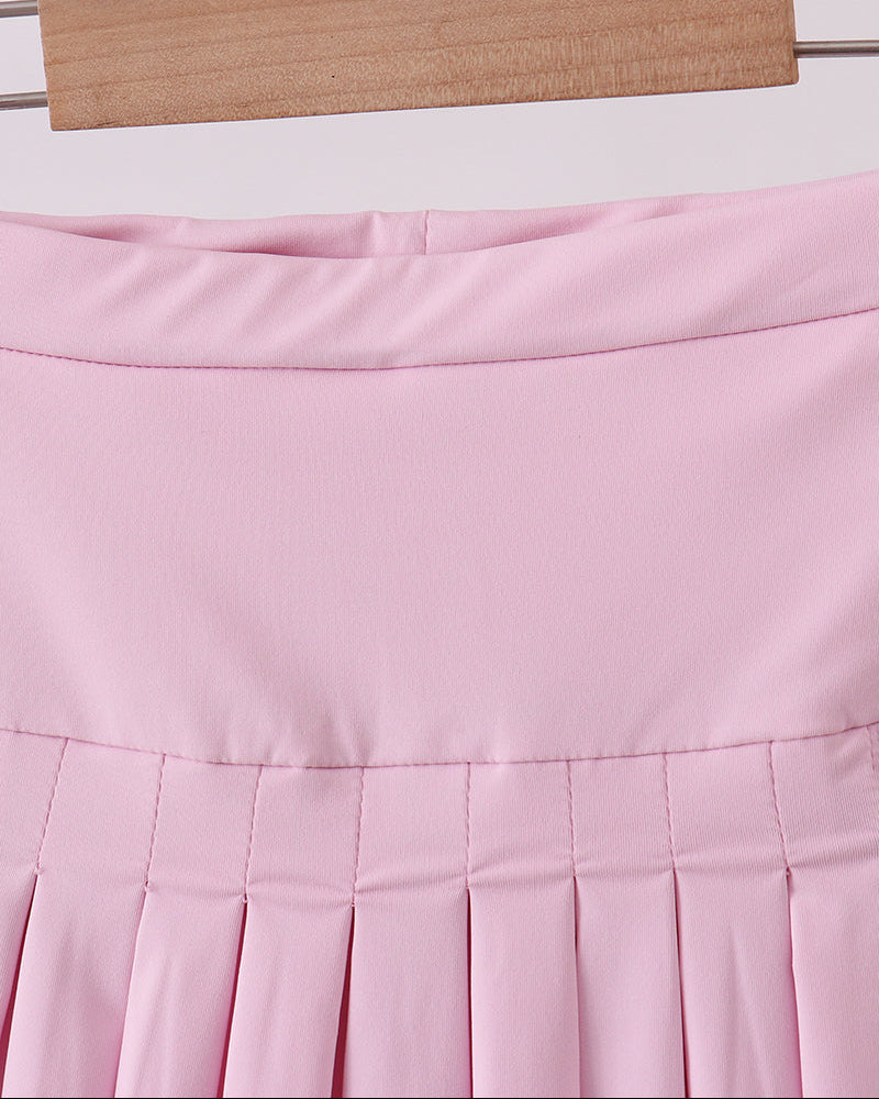 Pink pleated skirt on a hanger against a light background