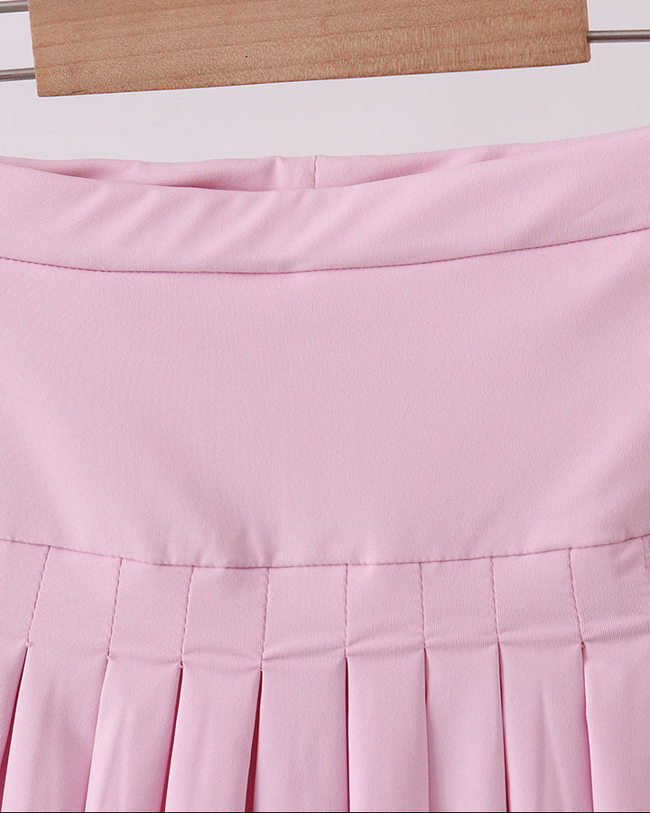 Pink pleated skirt on a hanger against a light background