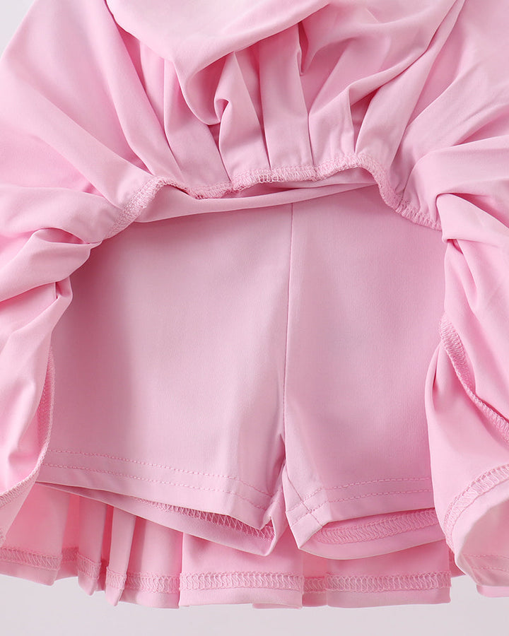 Pink skorts with ruffled sleeves and hem on a light gray background