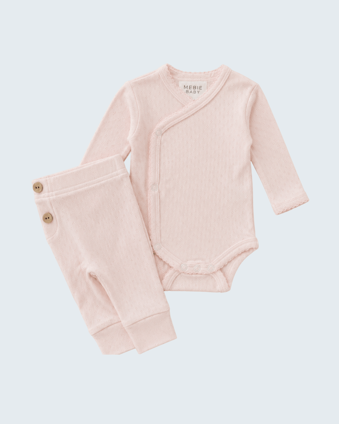 Pink baby bodysuit and pants set on a light gray background
