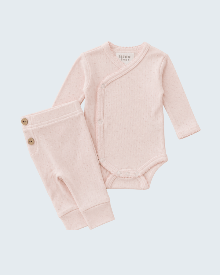Pink baby bodysuit and pants set on a light gray background