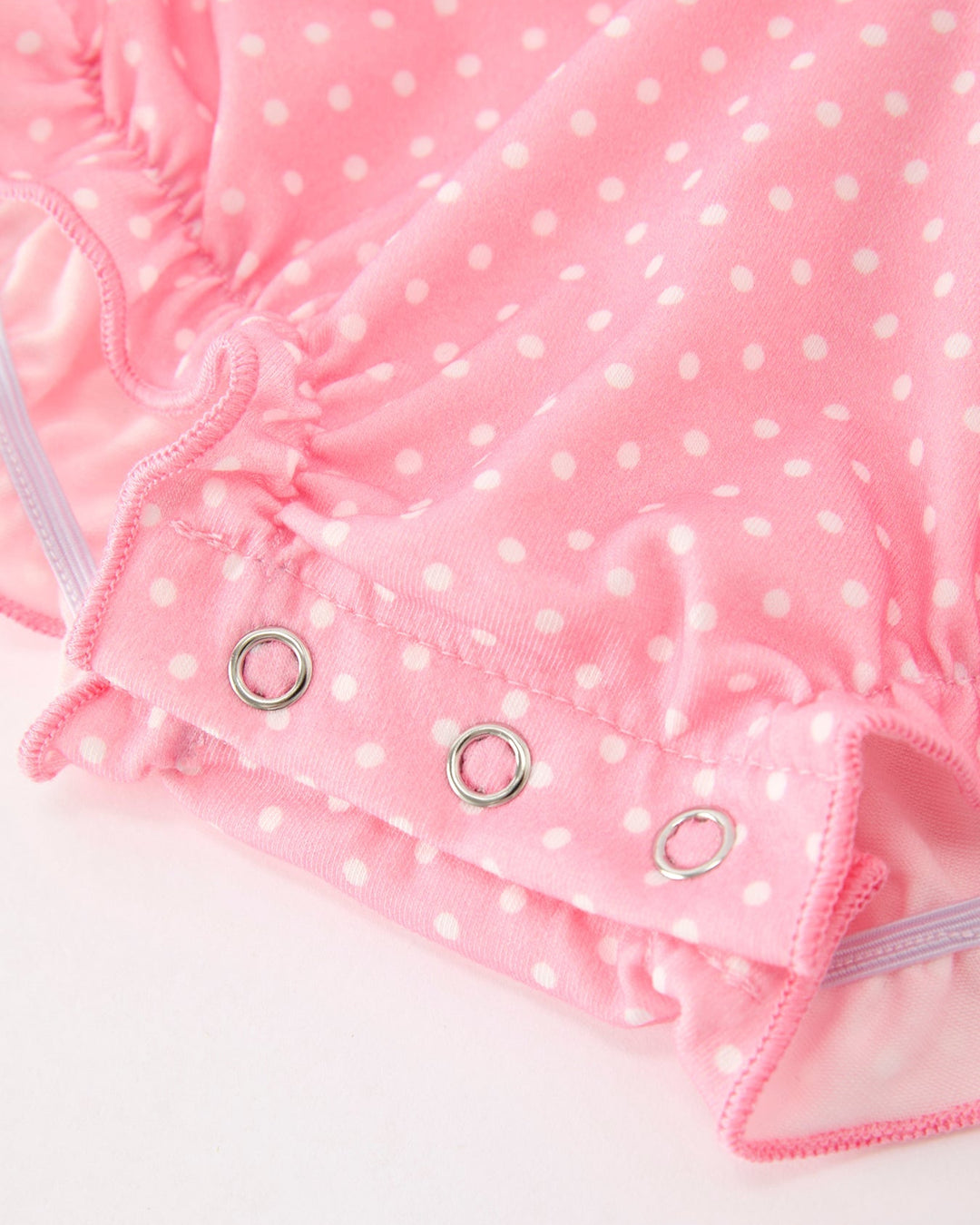Pink polka-dot romper with snap button closure and ruffled leg openings
