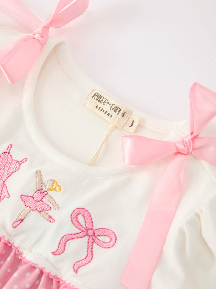 Cream bodice dress with pink bow straps and size tag, embroidered ballet motifs