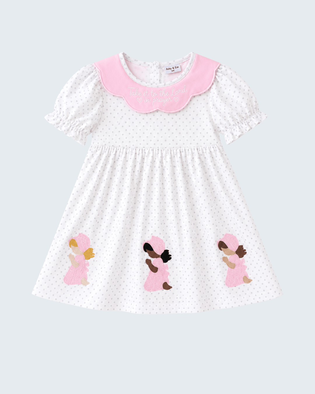 White polka-dot dress with pink scalloped collar and three angel appliques