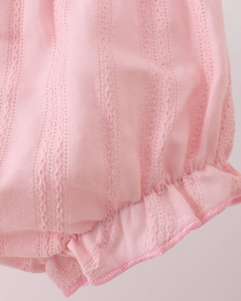 Close-up of pink fabric with lace trim on a light background