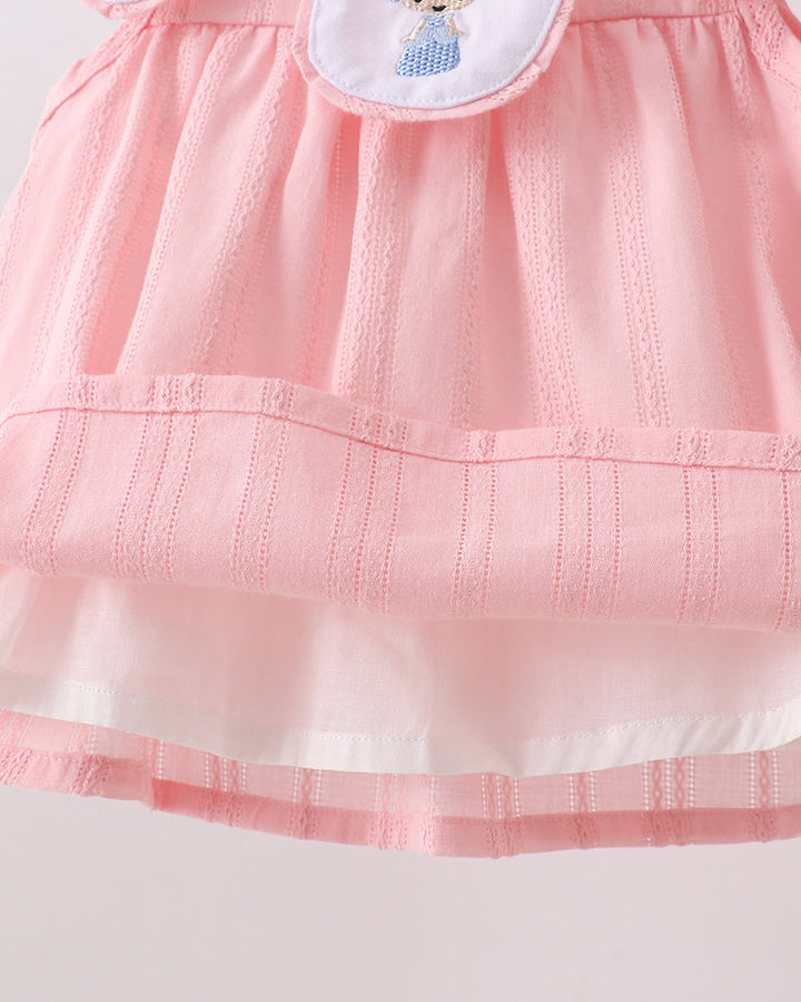 Close-up of a pink dress with a white collar on a light gray background
