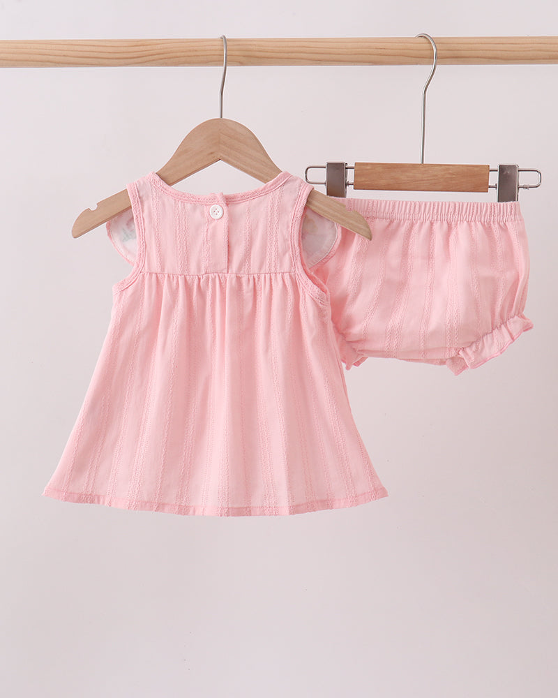Pink baby dress and bloomers set hanging on a rack against a light background