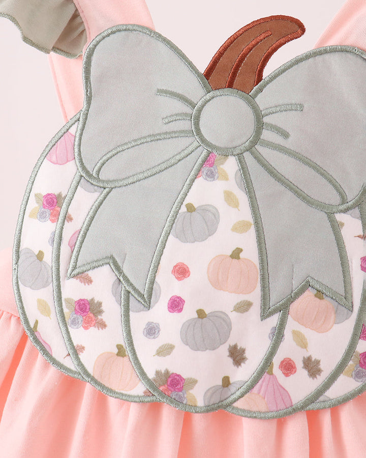 Pink dress with large pumpkin appliqué, bow detail, and ruffled skirt