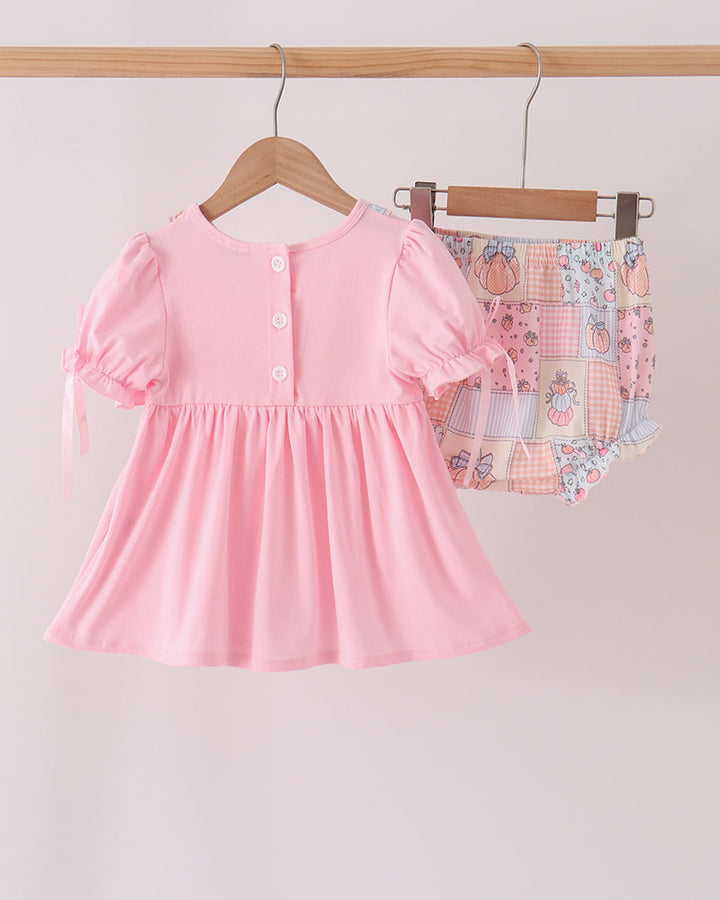 Pink embroidered ruffle dress with pumpkin print bloomer set on hangers