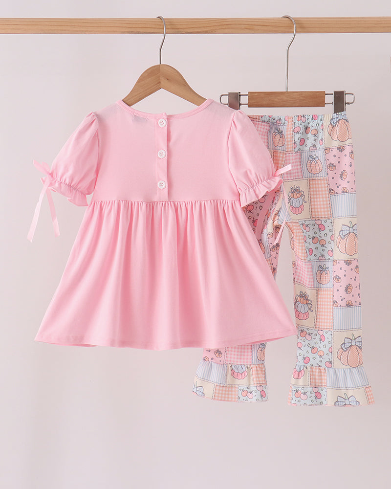 Pink ruffle top and patchwork pajama pants set on hangers