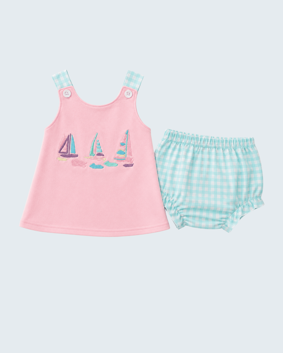 Pink sleeveless top with sailboat design and green checkered bloomers on a light gray background