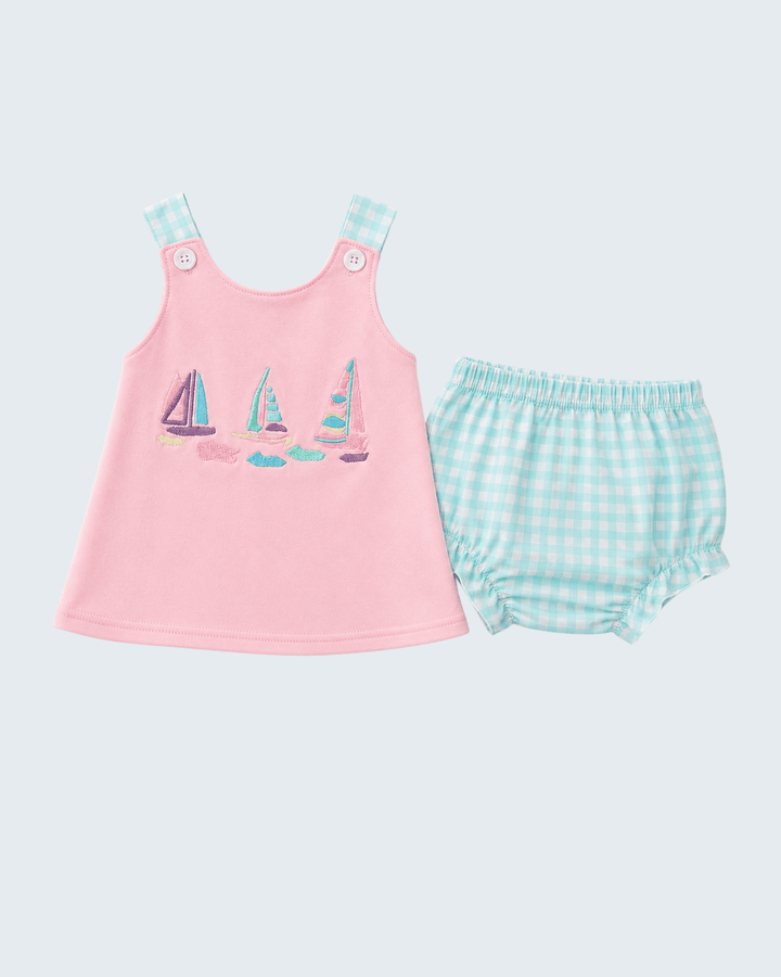 Pink sleeveless top with sailboat design and green checkered bloomers on a light gray background