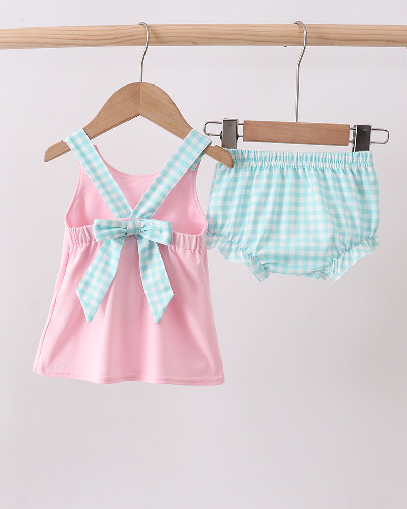 Pink tank top with blue checkered straps and matching shorts on a wooden hanger against a white background.