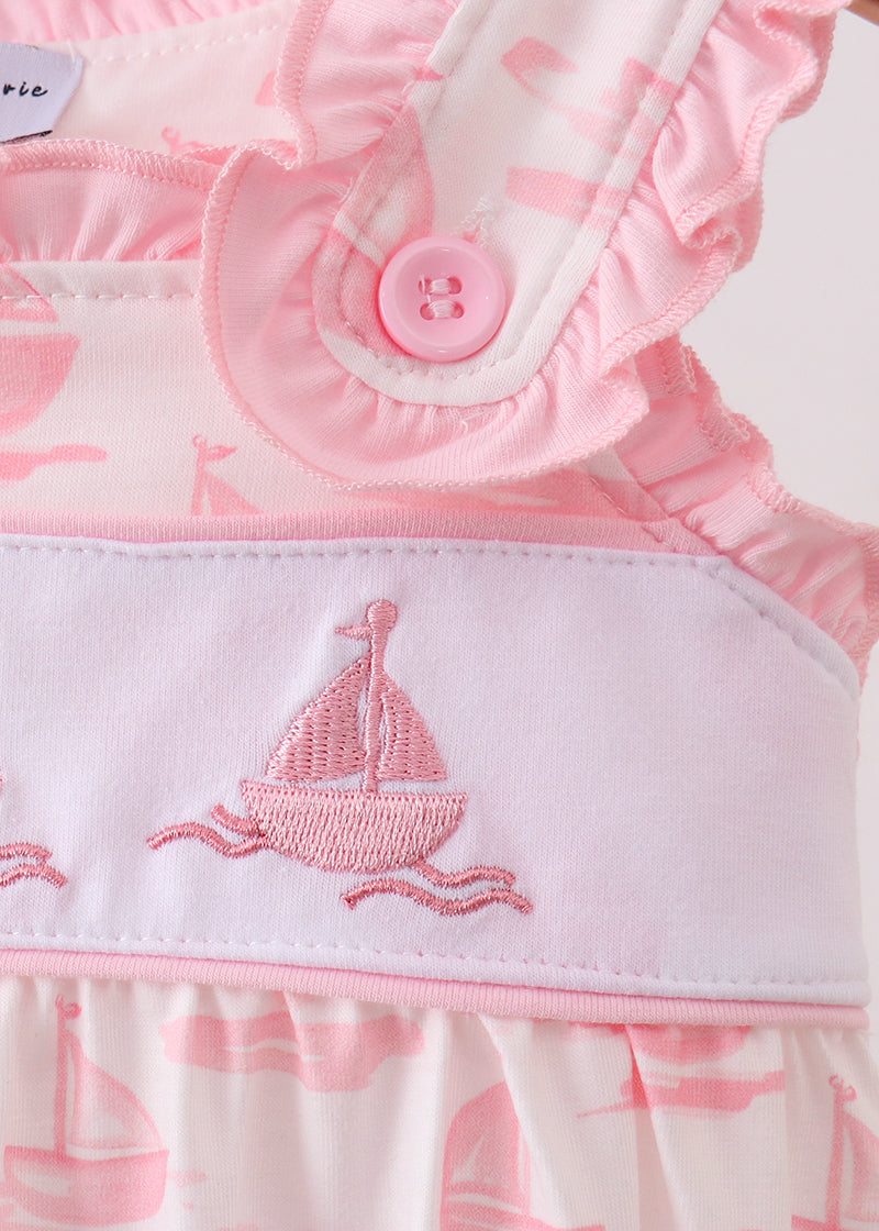 Pink baby romper with sailboat design and button detail on a white background