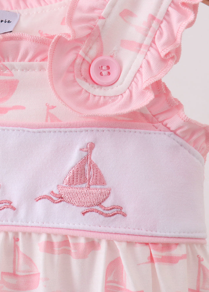 Pink baby romper with sailboat design and button detail on a white background