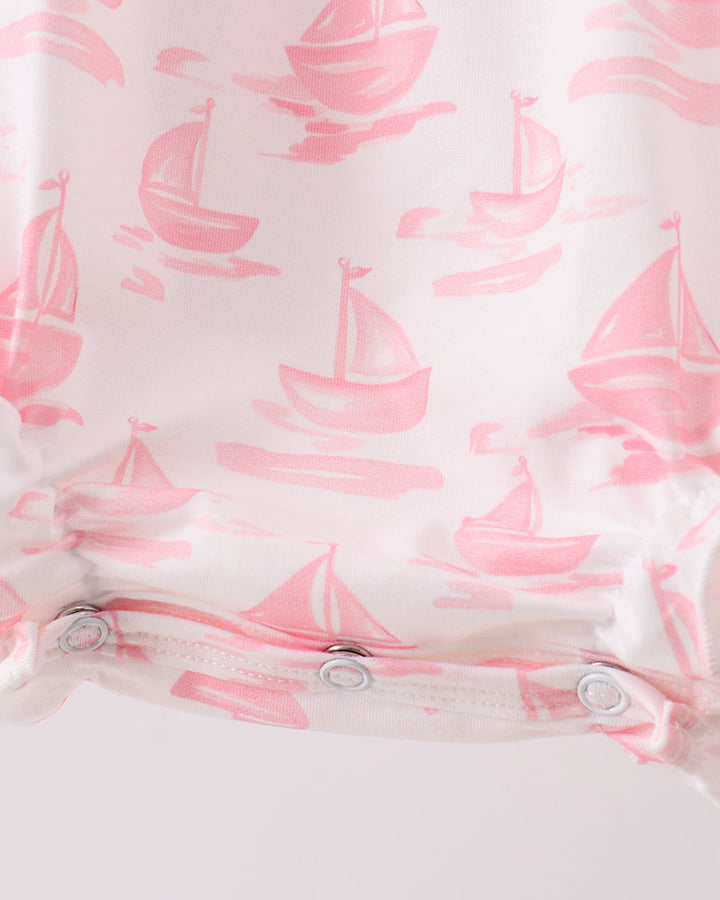 Baby romper with pink sailboat pattern on a white background
