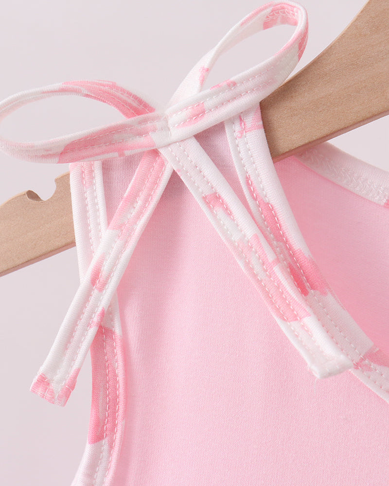 Pink and white lace trim on a wooden hanger against a light pink background