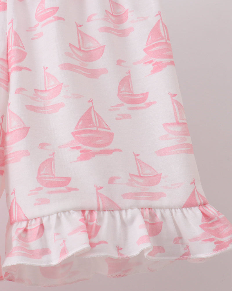 White shorts with pink sailboat pattern on a light gray background