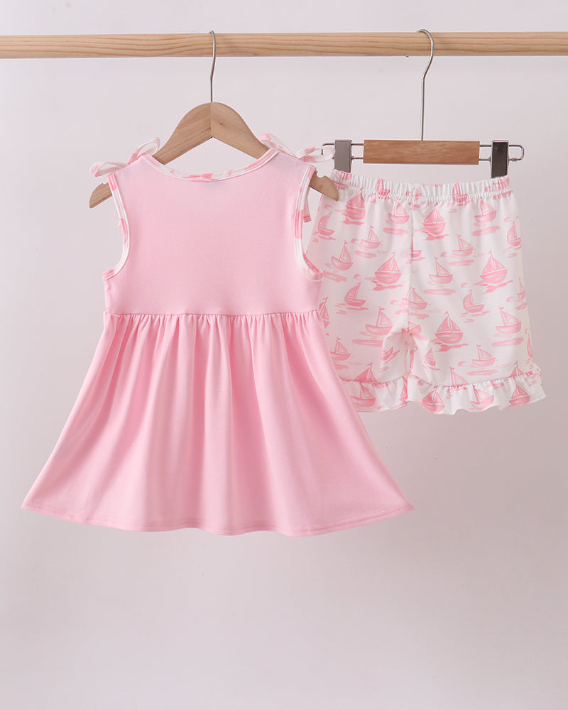 Pink dress and shorts set hanging on a rack against a light background
