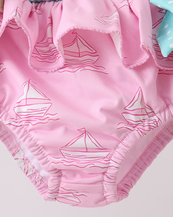 Pink swim bottoms with sailboat pattern on a light gray background